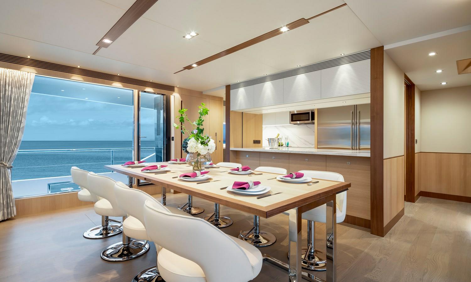 FD87 Aqua Life dining table with place settings and eight chairs, and view of galley.